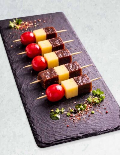 Banderillas de atún, queso y guinda servidas sobre tabla de pizarra.